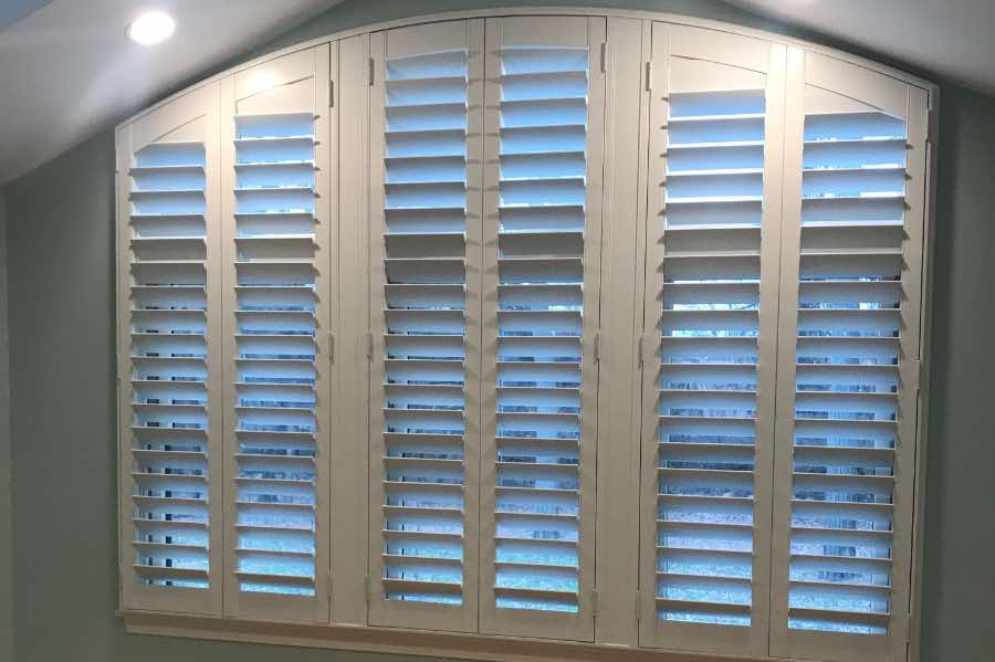 White Polywood shutters on a large arched window